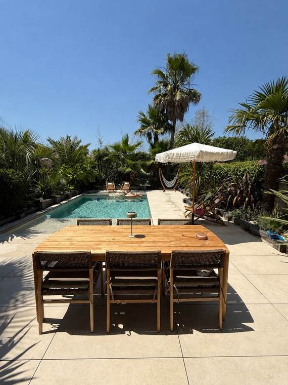 Grande table en bois, parasol crème et hamac sous les palmiers
