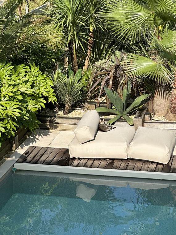 Bain de soleil sur le deck en bois, entouré de palmiers et d&rsquo;agaves
